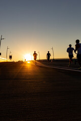 Multiple runners running on a road towards the sunrise