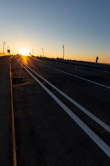 Obraz na płótnie Canvas Vertical shot of road on a bridge leading towards sunrise
