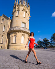 Portrait in red dress in beautiful castle, attractive girl walking