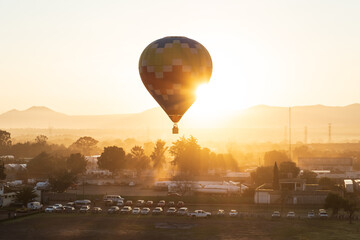 A Hot Air Balloon rises above the countryside as the sun rises