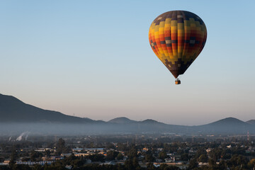 Fototapeta na wymiar A Hot Air Balloon rises above the countryside as the sun rises