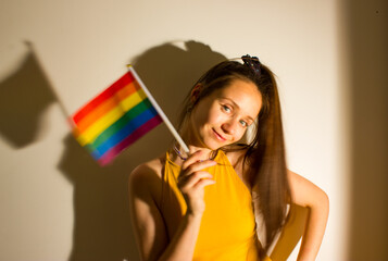 Beautiful young woman, girl holding LGBT flag in hand celebrating Pride Month. Cute sexy girl has...