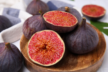Fresh ripe purple figs on wooden plate, closeup
