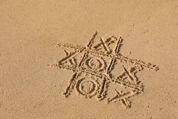 Tic tac toe game drawn on sandy beach