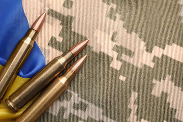 Military bullets and Ukrainian flag on pixel camouflage, flat lay. Space for text