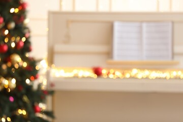 Blurred view of white piano with fairy lights indoors. Christmas music