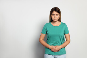 Obraz premium Young woman suffering from menstrual pain on grey background. Space for text