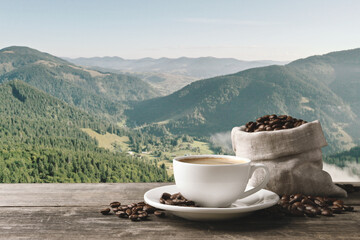 Cup of aromatic hot coffee on wooden table and beautiful view of mountain landscape. Space for text