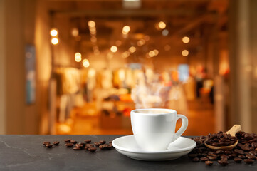 Cup of aromatic coffee and beans on grey table indoors
