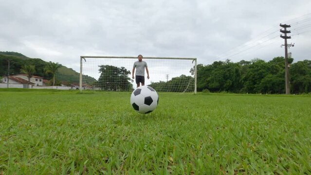 Kicking a soccer ball towards the camera. Soccer ball rolling on green grass of soccer field