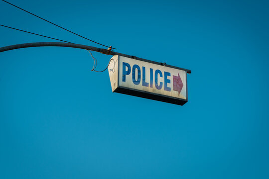 A dirty sign pointing to a police station.