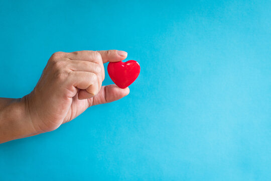 Heart Health Concept. Man's Finger Holding A Red Heart Shape. Copy Space.