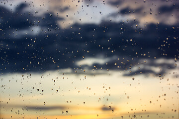 Raindrops background. Overcast weather, rain on a sunny day. Glass surface dotted with lots small...