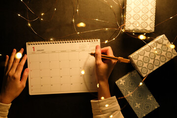 New Year planner concept for motivation. Women writes in planner notebook. Flat lat and top view...