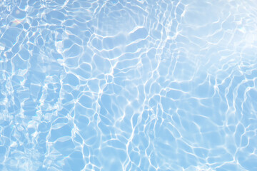 Bluewater waves on the surface ripples blurred. Defocus blurred transparent blue colored clear calm water surface texture with splash and bubbles. Water waves with shining pattern texture background.