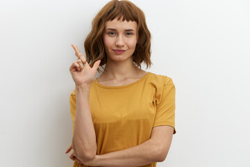 a funny, emotional, beautiful woman smiles broadly and gestures with her fingers towards an empty space on the background for inserting an advertising layout