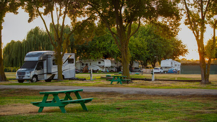 Camping in a small class B motor home under the trees at sun down