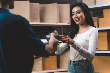 happiness businesswoman paying for her order with credit back card with delivery man from shipping company. Young women with new business about online shopping in home office and small store.