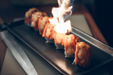 The chef is burning salmon, fish, crab, tuna and squid sushi. sushi is a street food of japan and...