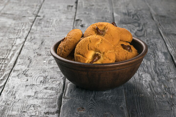 A large deep bowl with fresh oatmeal cookies on a rustic table.