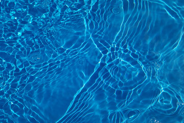 Defocus blurred transparent blue colored clear calm water surface texture with splashes and bubbles. Trendy abstract nature background. Water waves in sunlight with copy space. Blue watercolor shining