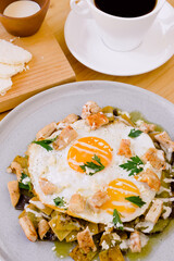 Mexican food, breakfast of chilaquiles with egg, cream, cheese and coffee.