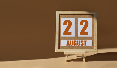 August 22th. Day 22 of month, Calendar date. Cork board, easel in sunlight on desktop. Close-up, brown background.  Summer month, day of year concept