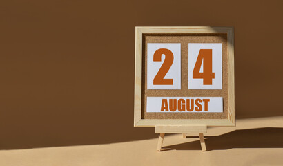 August 24th. Day 24 of month, Calendar date. Cork board, easel in sunlight on desktop. Close-up, brown background.  Summer month, day of year concept
