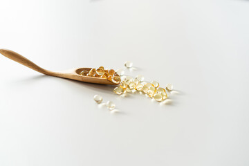 Vitamins on a white background. Capsules on spoon suitable for: fish oil, omega 3, omega 6, omega...
