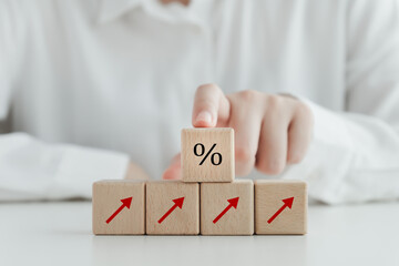 Interest rate finance and mortgage rates concept. Arrow up and hand touch on percentage sign on wooden block. financial growth, interest rate increase, inflation, sale price and tax rise concept.