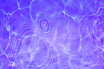Defocus blurred transparent purple colored clear calm water surface texture with splashes and...