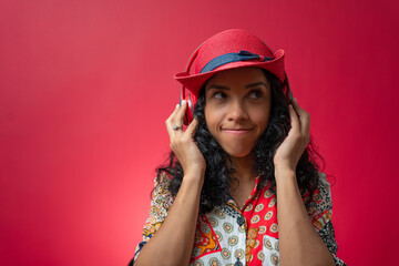 Portrait of a latin woman feeling happy listen music in headphones isolated on red background.
