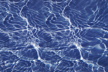 Defocus blurred transparent blue colored clear calm water surface texture with splashes and bubbles. Trendy abstract nature background. Water waves in sunlight with copy space. Blue watercolor shining