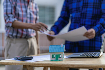 Concept of two young asian engineers and female architect discussing construction from industrial building project plans.