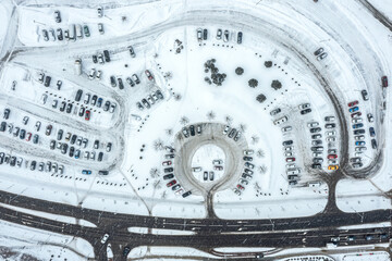 urban parking lot, covered with snow at winter season during snowfall. aerial top view.