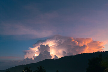Lightning flashes through the colorful cloud over mountain in the sunset sky