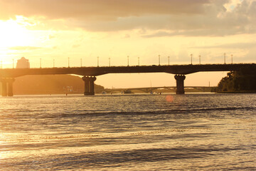 Car bridge silhouette evening sunset twilight. Yellow cloudy sky. Kyiv panorama