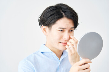 ハンドミラーを見る目が痛い男性