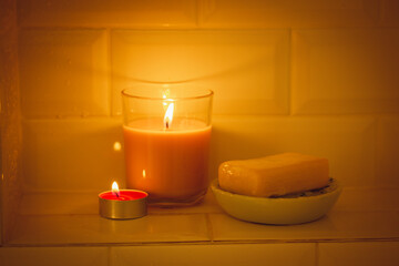 Natural soap, candle with a burning flame in a shower bathtub. Body skin care.