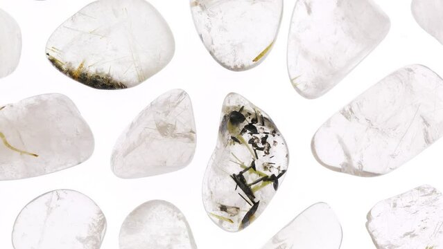Rutilated quartz rare jewel stones texture on white light isolated background. Moving right seamless loop backdrop.