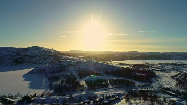 bird's eye view of a snowy winter mountain landscape under a bright sun in norway kirkenes