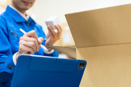 荷物を検品してタブレットPCでチェックする男性