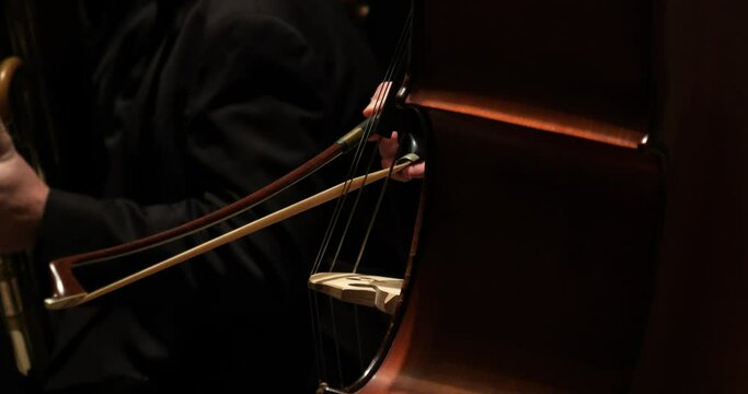 Extreme close up handheld shot of a talented violoncello player during a concert with orchestra in theatre to classical music by mozart