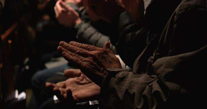 Close up slow motion shot of clapping hands during a concert with orchestra applauding the musicians after a successful performance