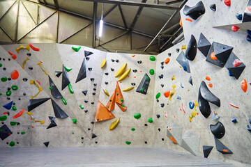 Wall for bouldering in gym with holds for climbing. Active extreme sport concept