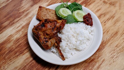 Ayam Bakar Kecap. soy sauce grilled chicken served with rice, Tempe bacem, fresh vegetables and sambal.