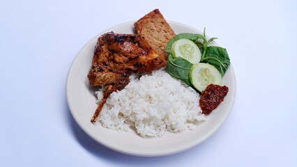 Ayam Bakar Kecap. soy sauce grilled chicken served with rice, Tempe bacem, fresh vegetables and sambal.