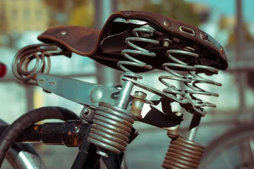Foto op Plexiglas Fiets Brown leather vintage bicycle saddle. Old leather cushion metal squeaky springs.
