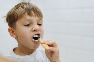 cute 5 years old boy brushing teeth with bamboo tooth brush in bathroom. Image with selective focus
