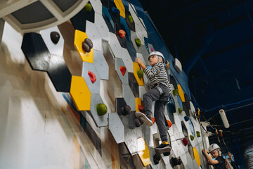 caucasian boy climbing in adventure park passing obstacle course. high rope park indoors